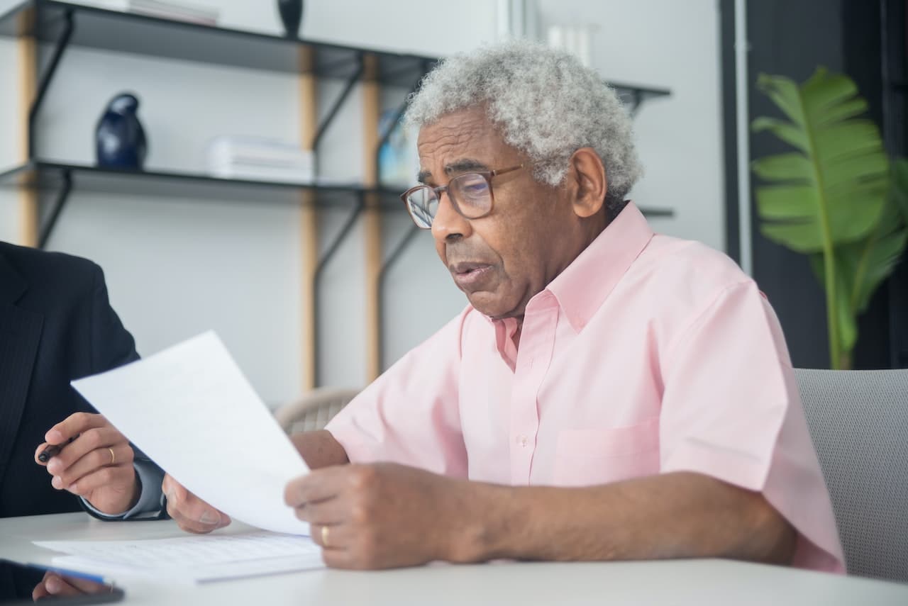 a man in a pink button up shirt reading a document