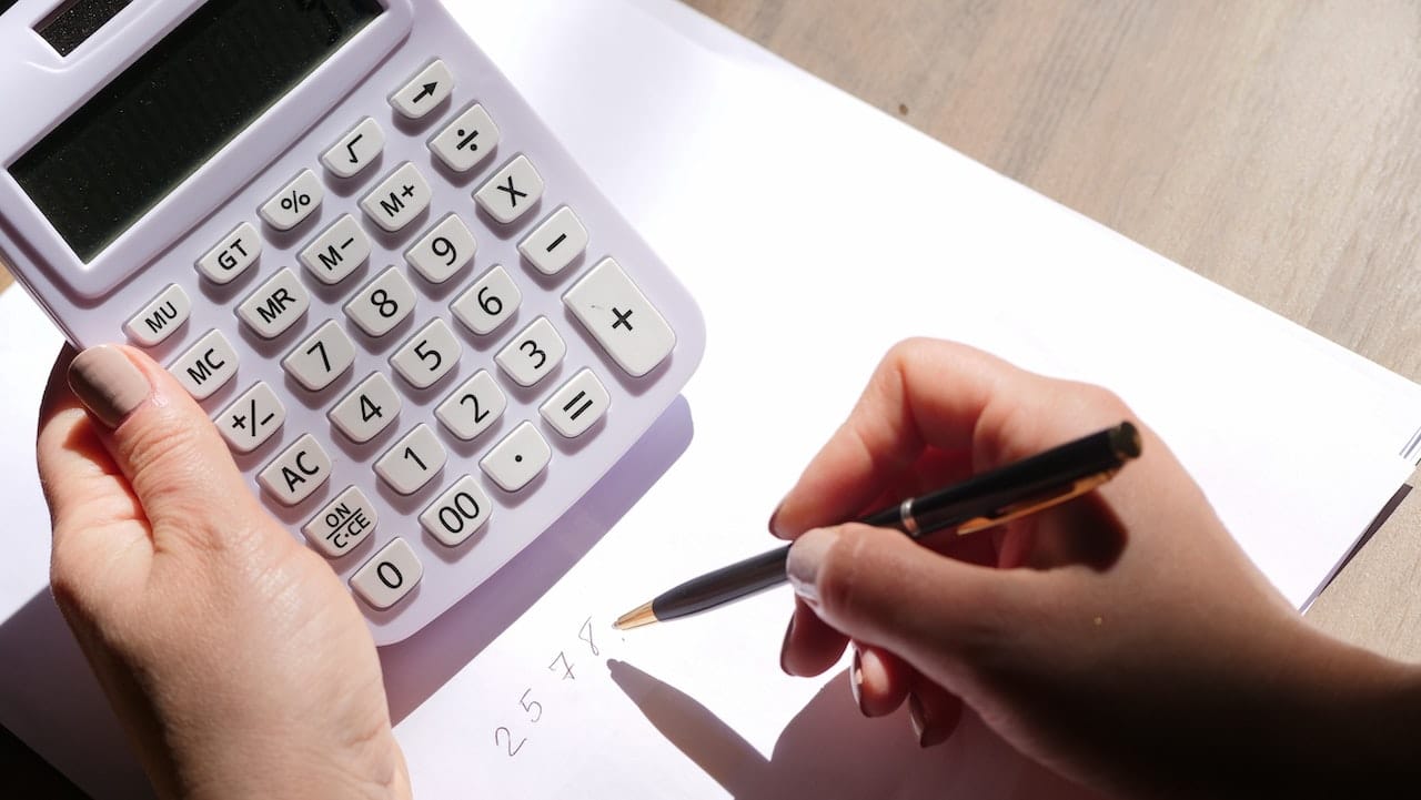 close up photo of person holding a pen and calculator