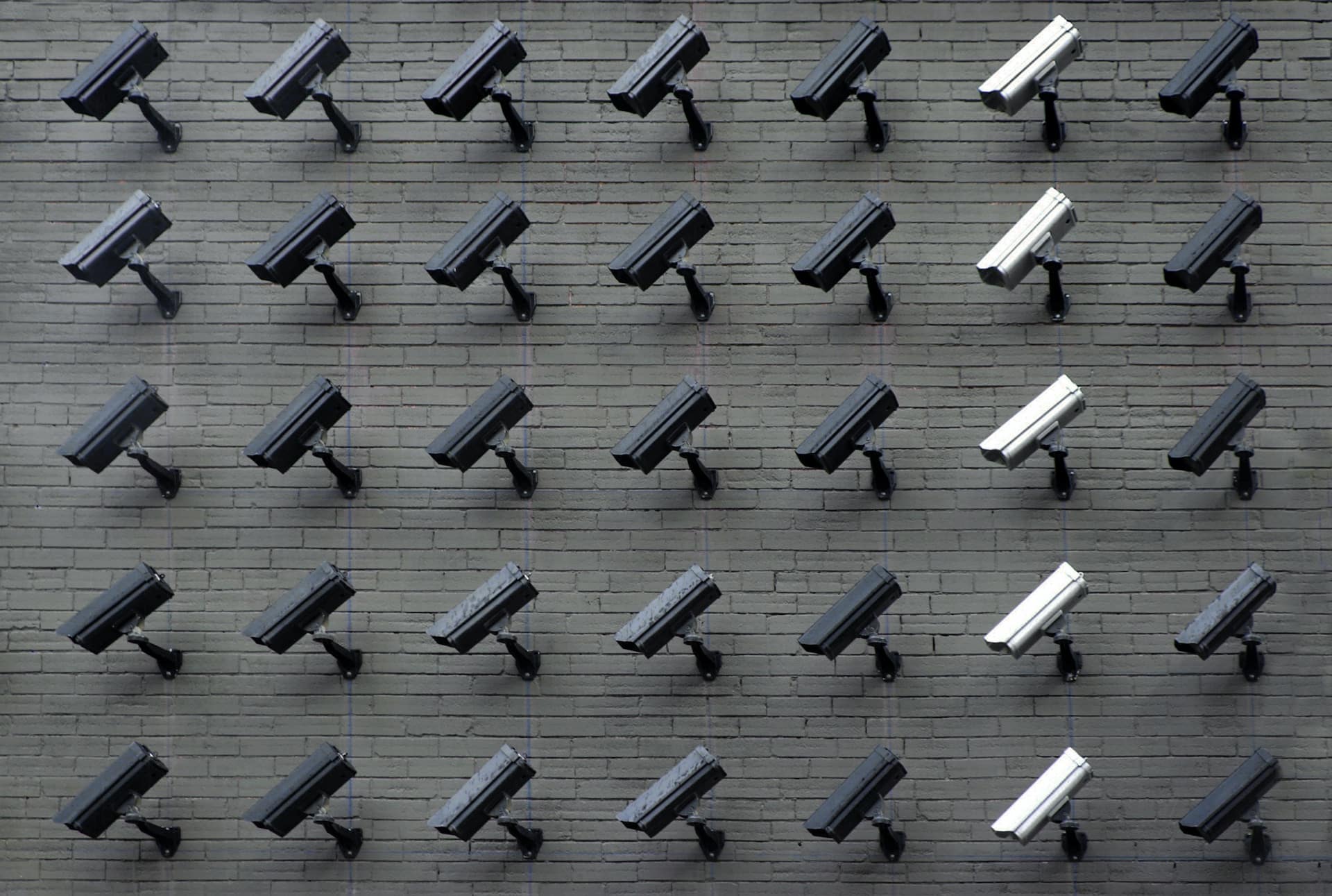 assorted colour security cameras mounted on a wall