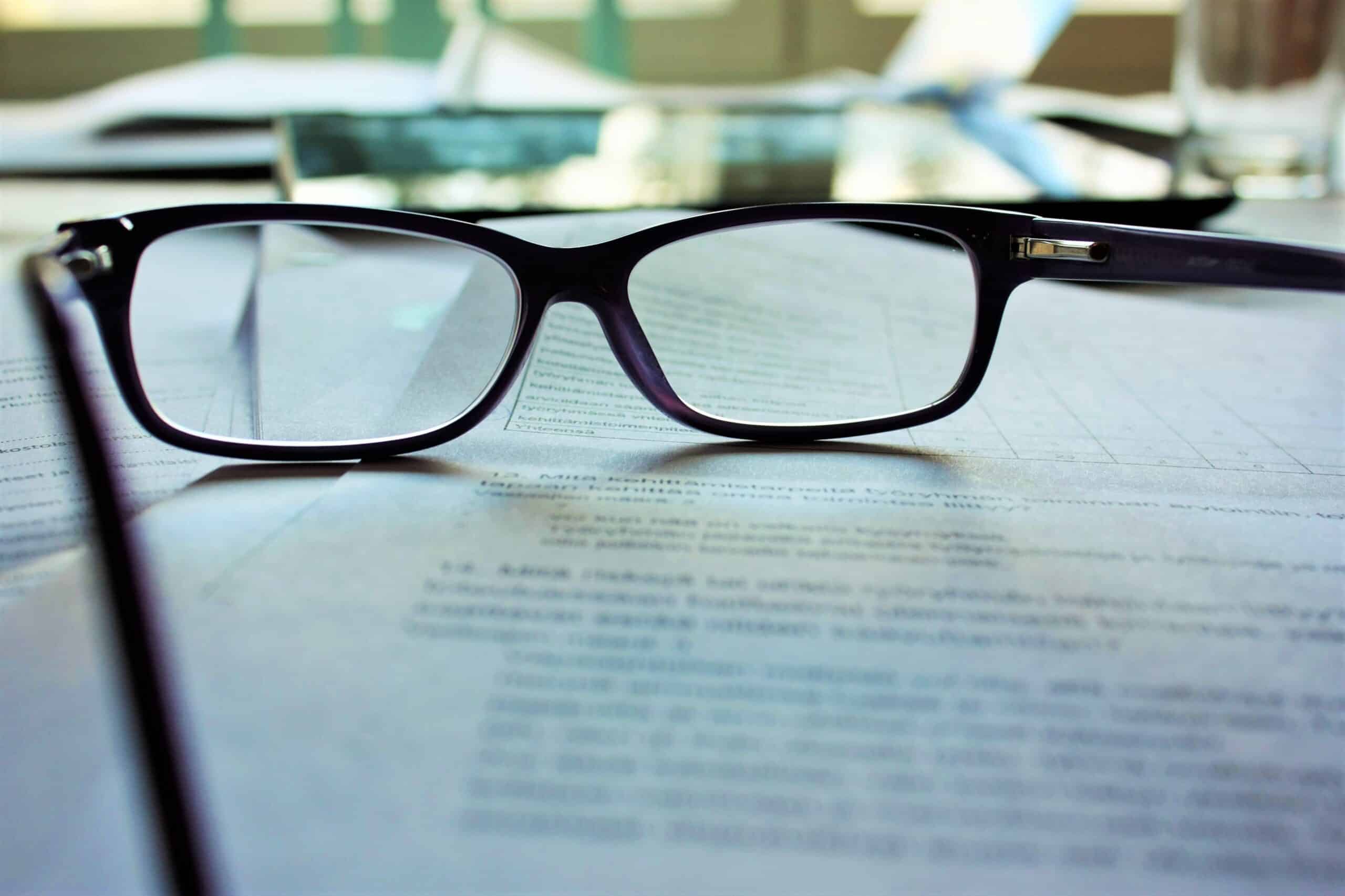 Glasses on top of a contract representing new legislation around non-compete clauses in new employment