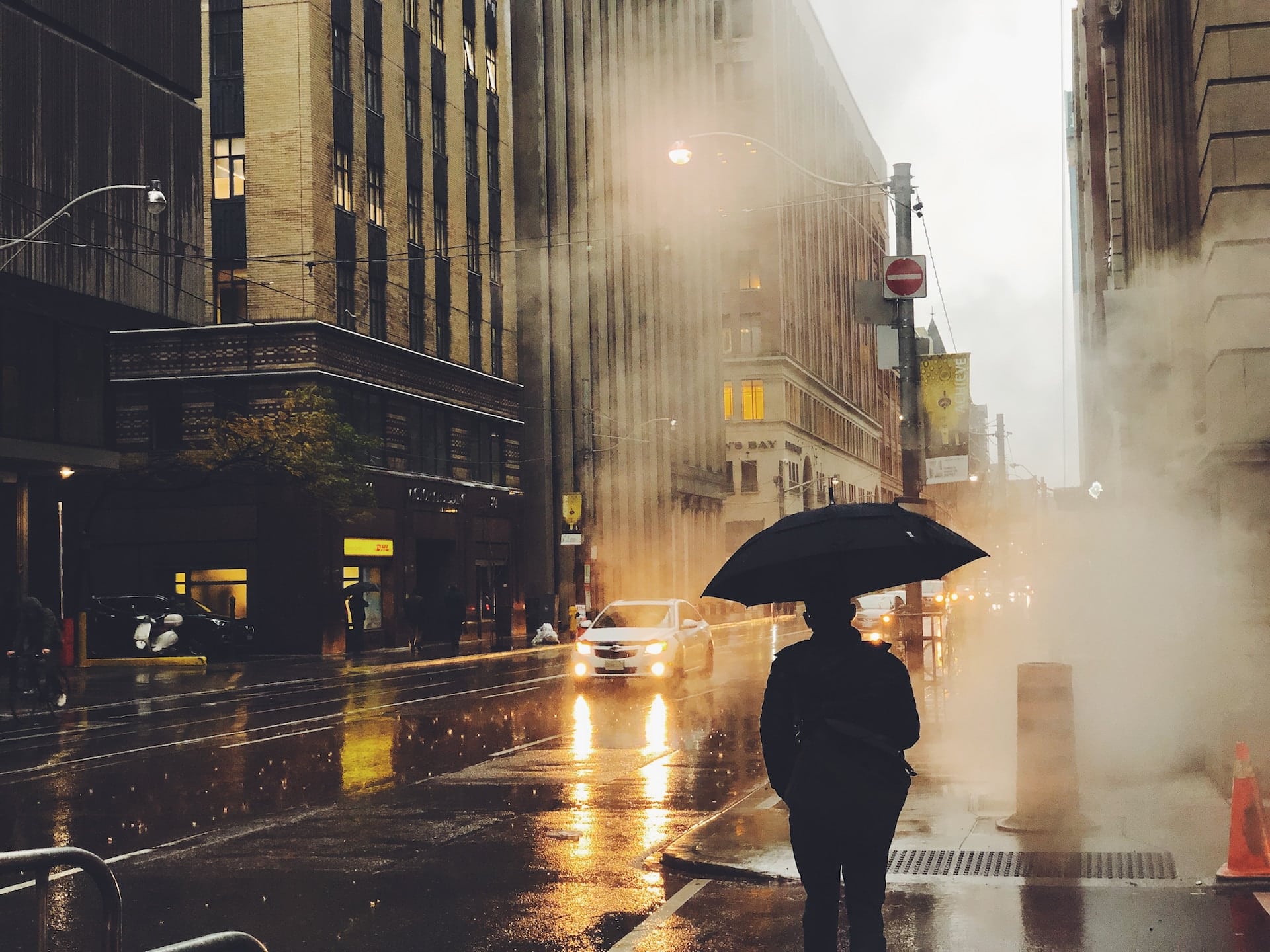 person holding umbrella walking in the rain in the city