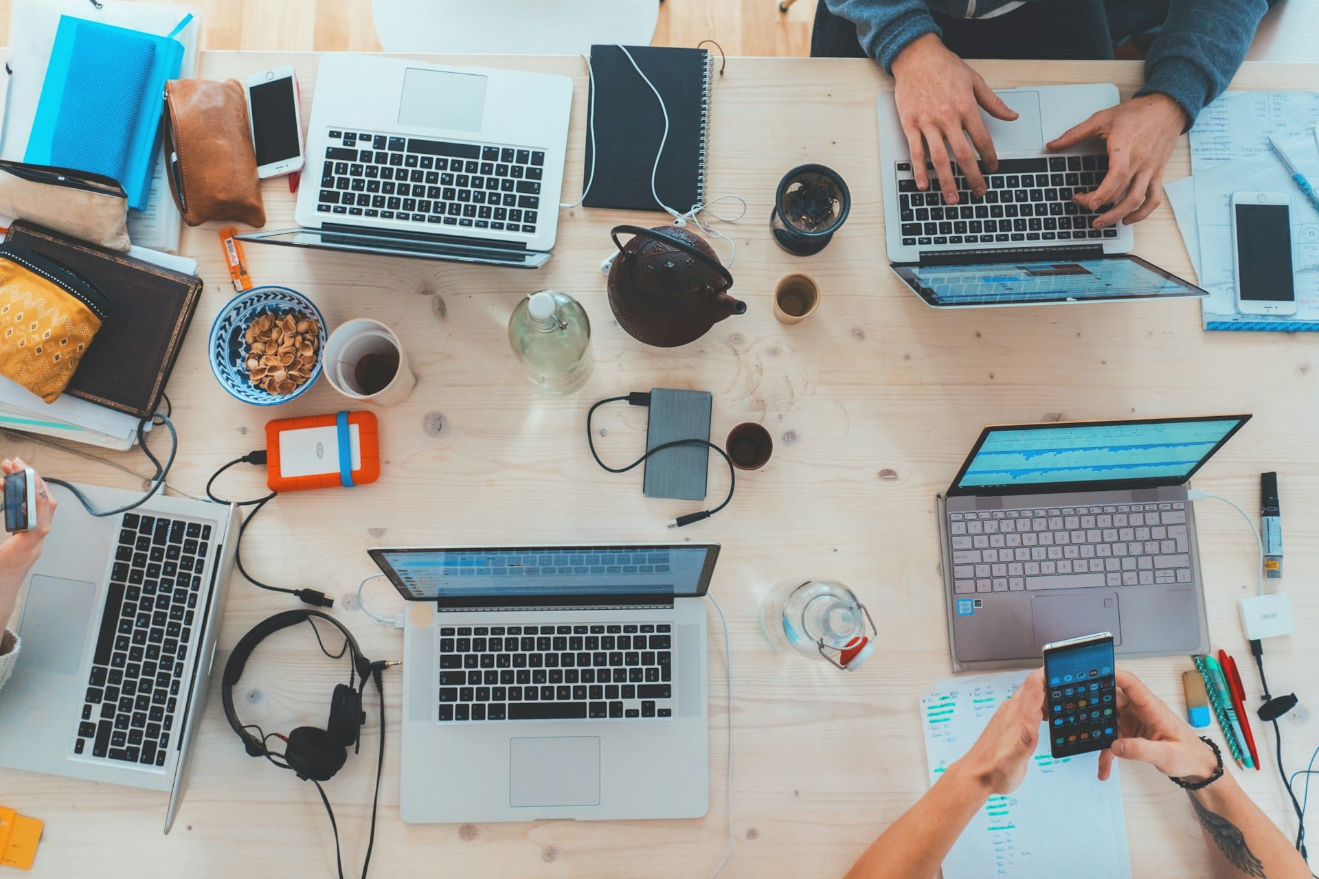 a table of people with laptops and work accessories