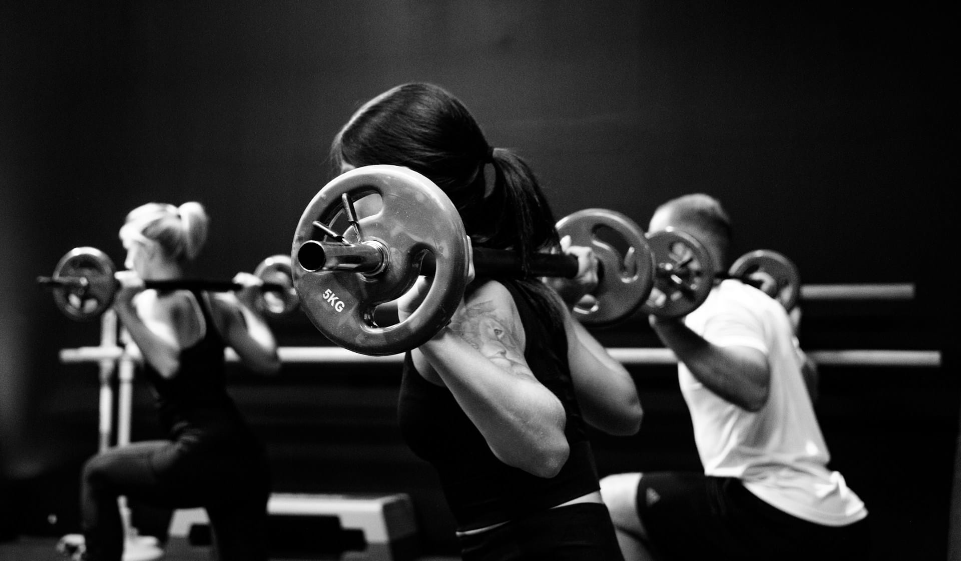 three people in a weight lifting class in a gym