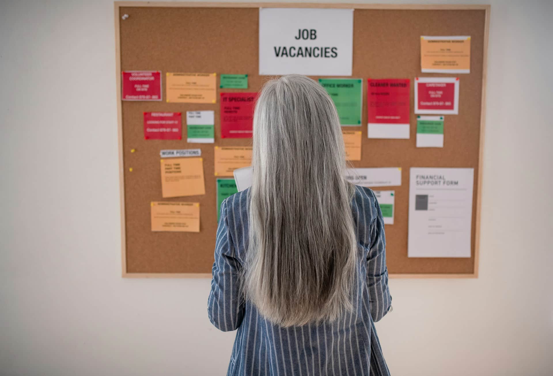 A woman looking at a Job Vacancies bulletin board, representing mitigation of damages in wrongful dismissal cases