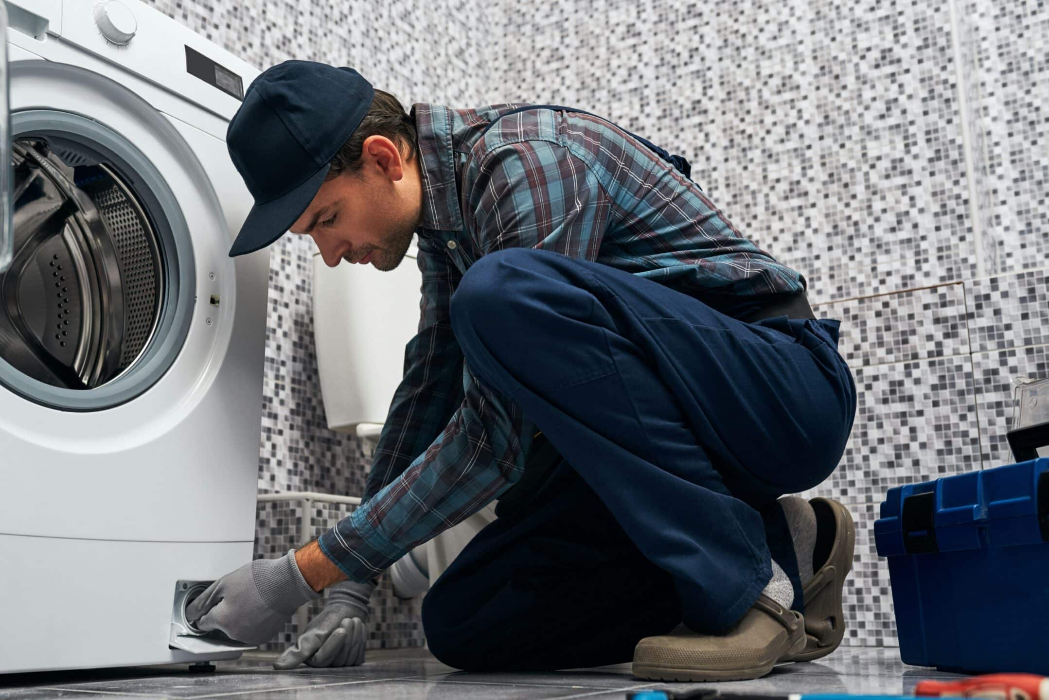 A maintenance worker fixing a laundry dryer, representing apartment superintendents and employment rights in Ontario