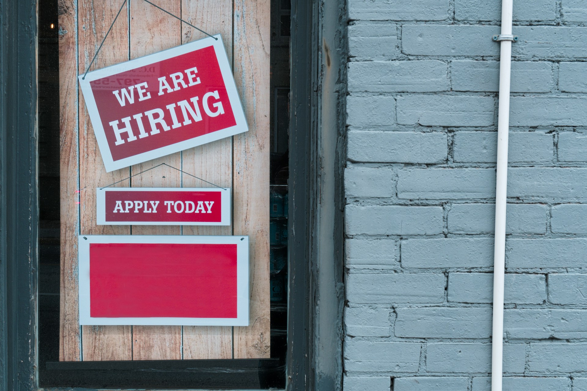 A glass door with a sign that reads, 'We're Hiring', representing Ontario pay transparency.