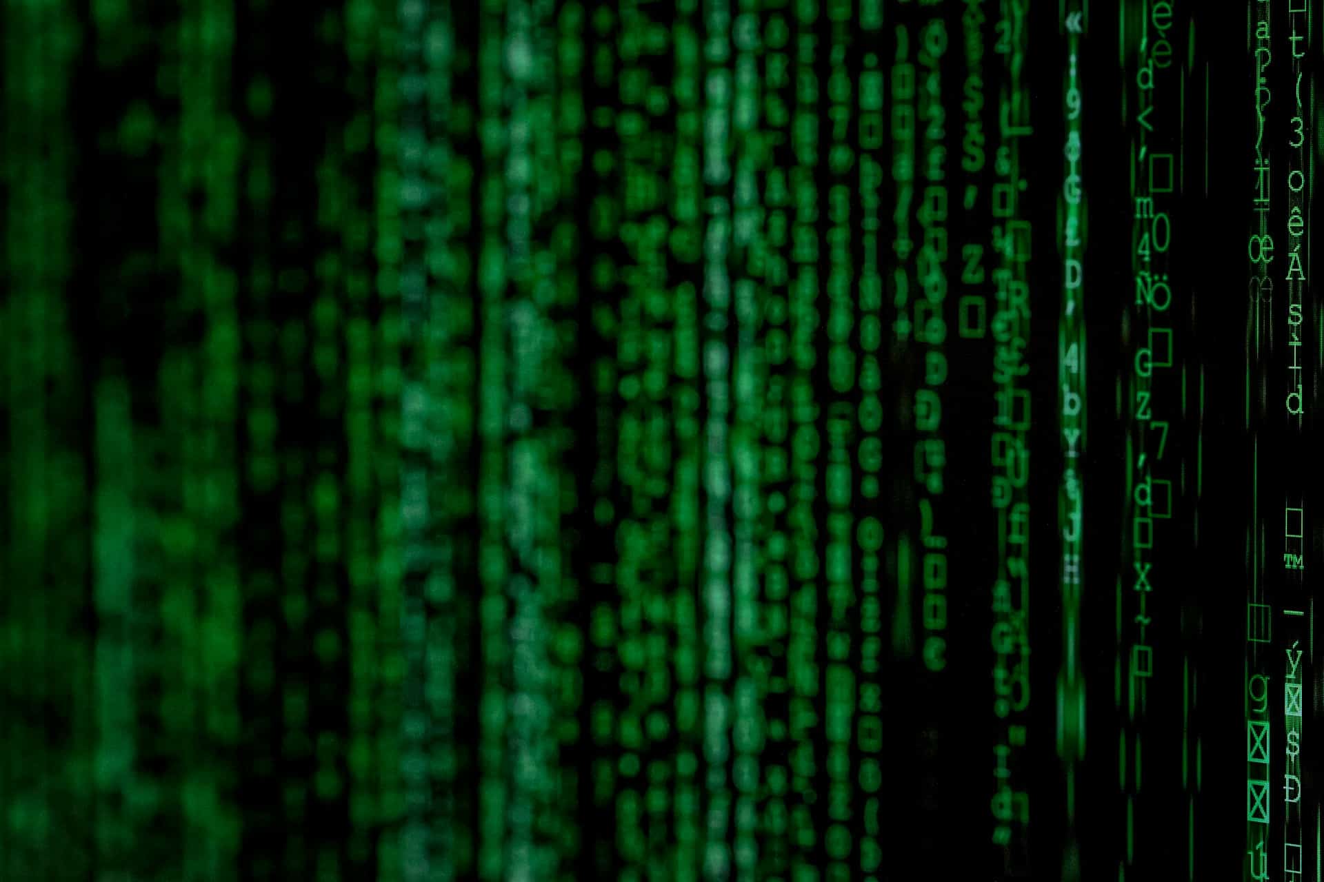 Blurred green code on a black background, representing algorithmic management.