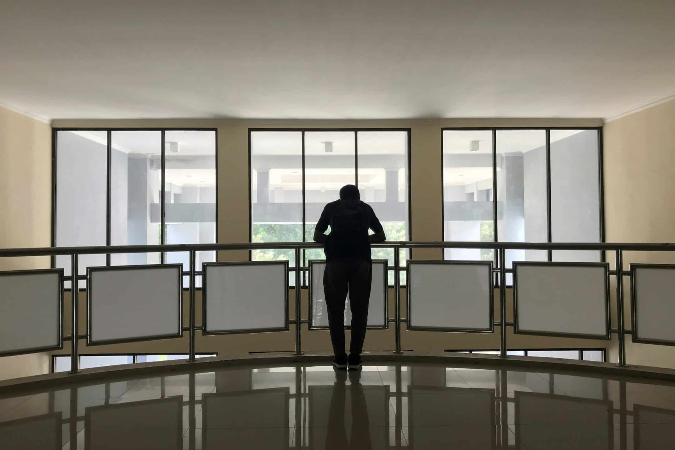 Silhouette of a person looking out of office windows, illustrating the risks of Ontario employee terminations and employer liability.